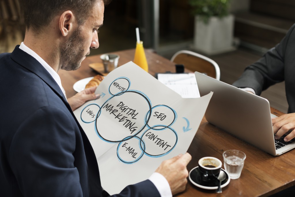 businessman holding a wide paper showing different aspects of digital marketing