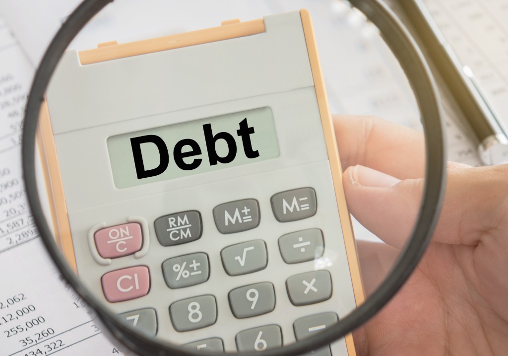 Debt concept text on calculator and magnifier