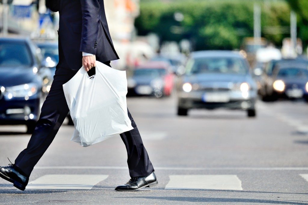 Man in suit with plastic bag crossing street