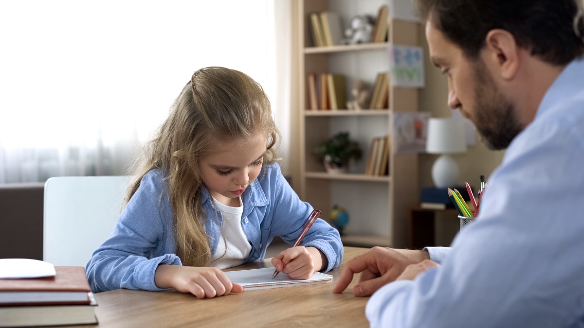 child writing with father