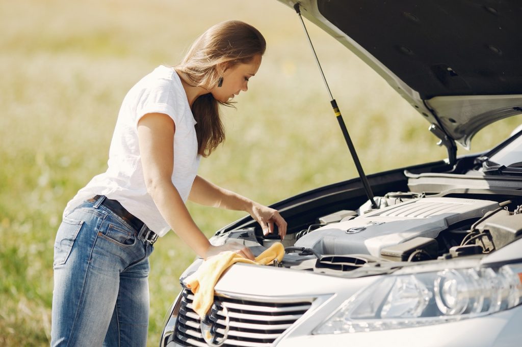 woman looking under the hood of her car