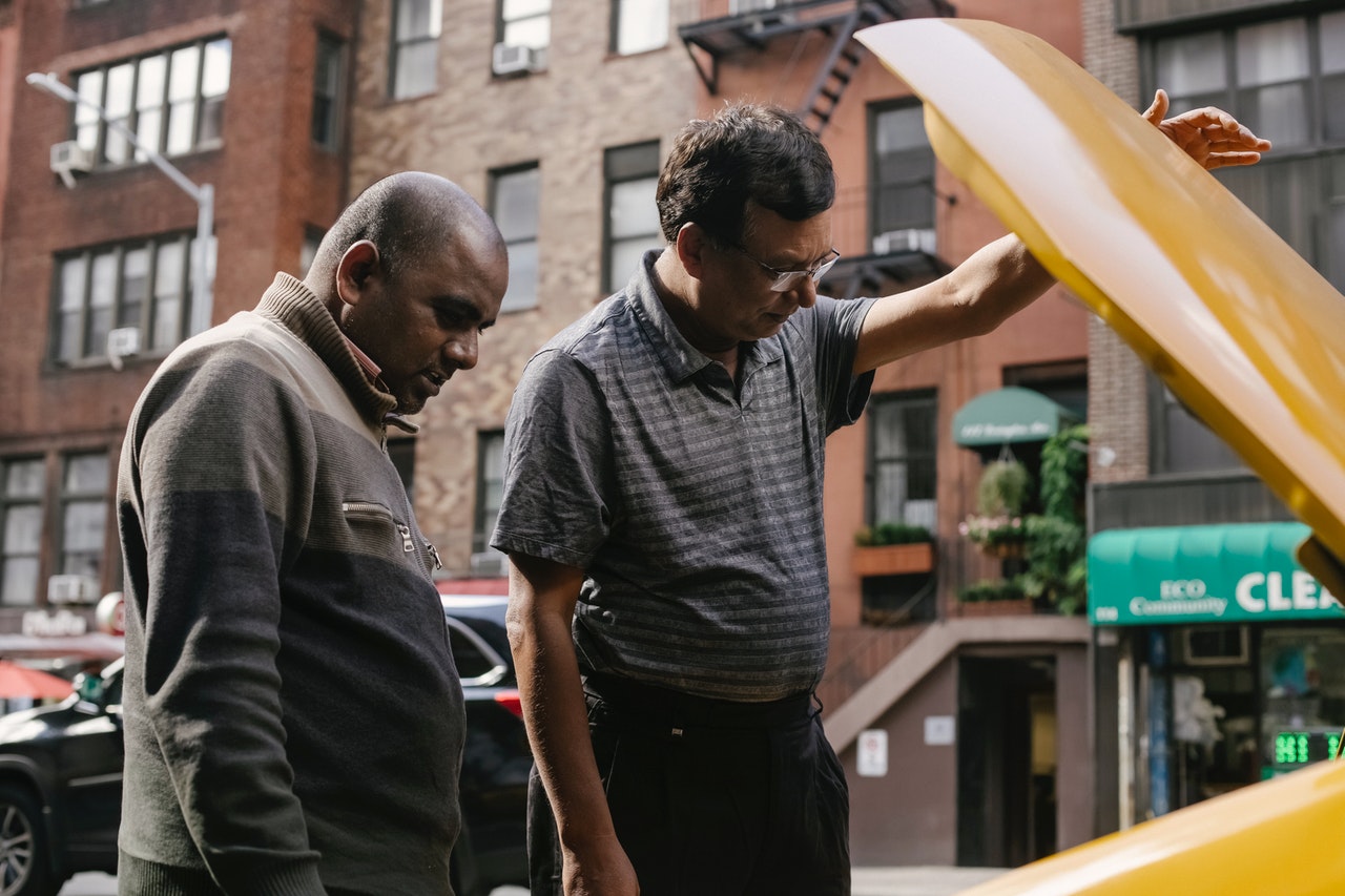 men looking under the hood of a car