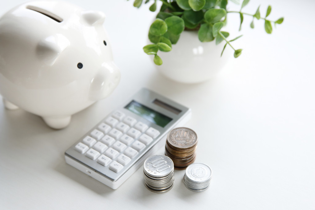 A piggy bank, calculator, stacks of coins, and a potted plant