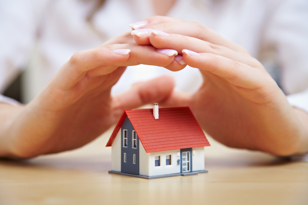 miniature house covered by hands