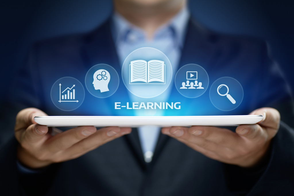 A person holding a tablet with E-learning icons