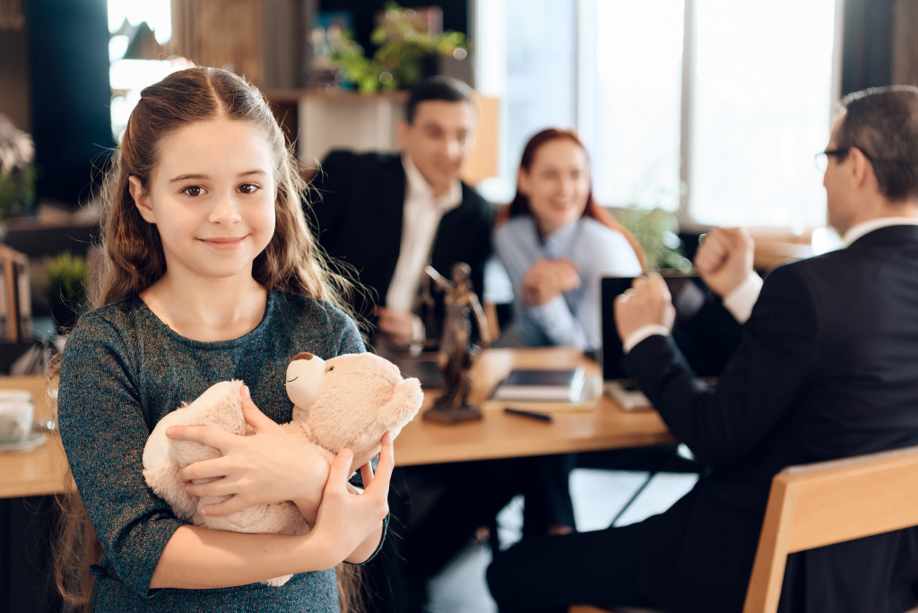 A smiling girl with parents in the background talking to a lawyer