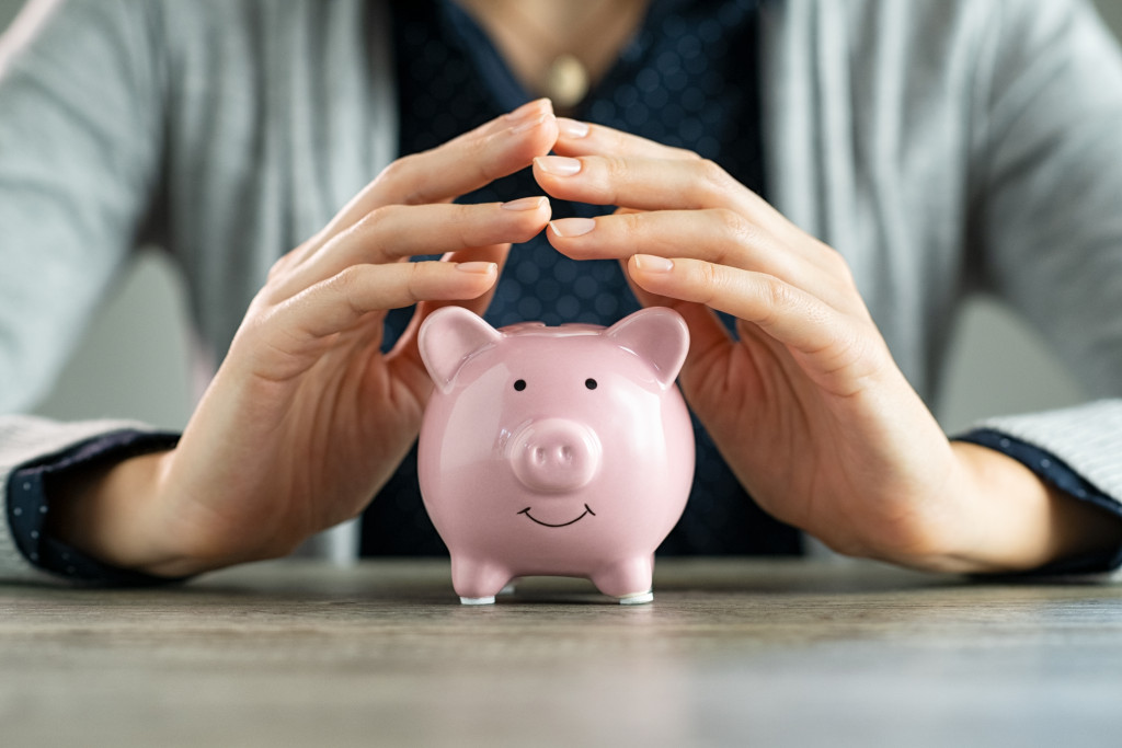 woman's hands protecting piggy bank concept of saving money