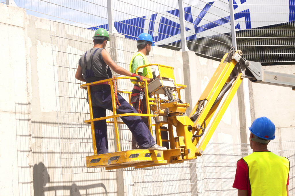 Two construction workers using a hydraulic platform for a construction project