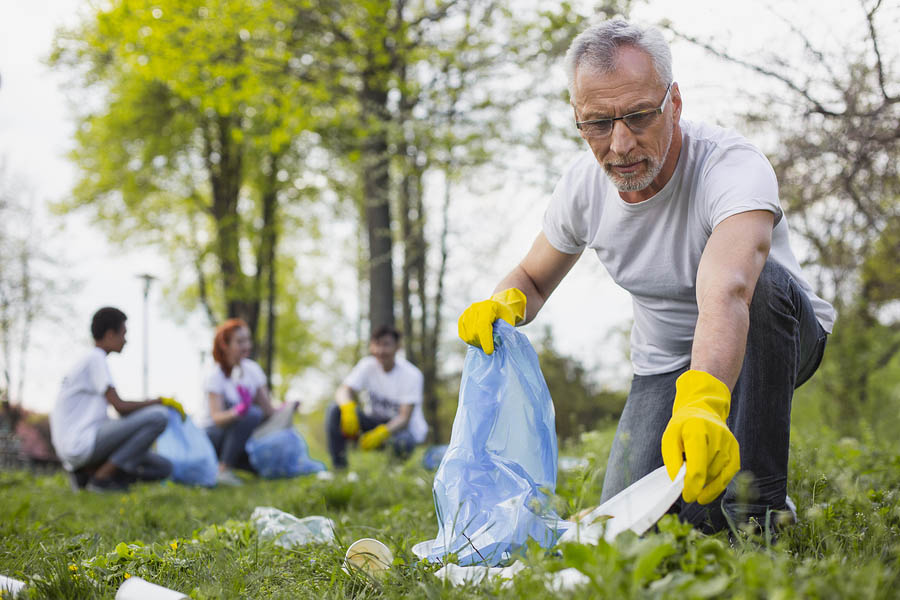 Precious nature. Concentrated senior volunteer holding garbage bag and looking at camera