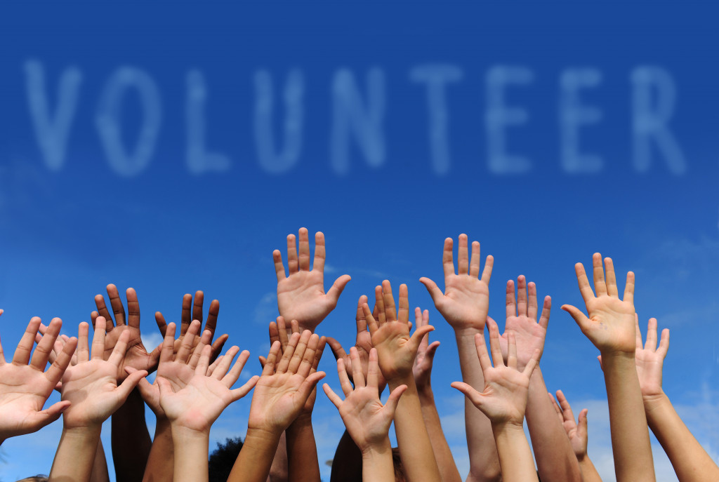 volunteer spelled in the clouds with hands raised