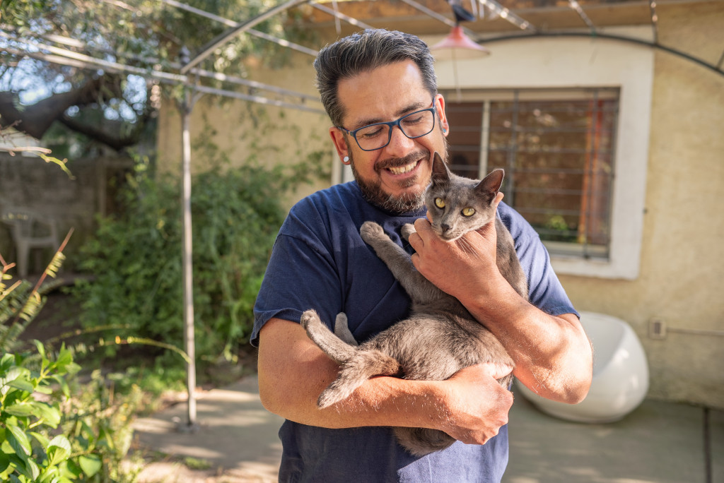 Mature man smiling while holding a gray cat.